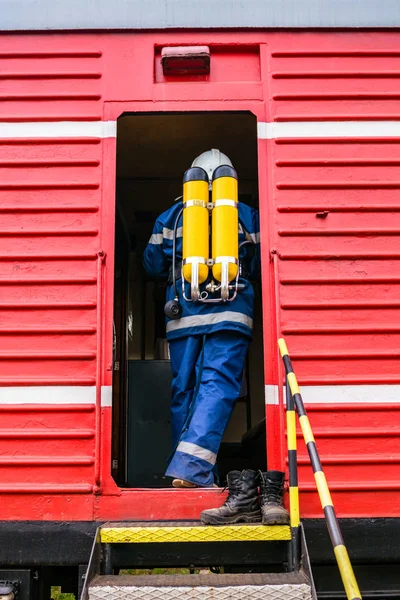 Fireman wearing protective uniform standing next to a fire train. — Stock Photo, Image