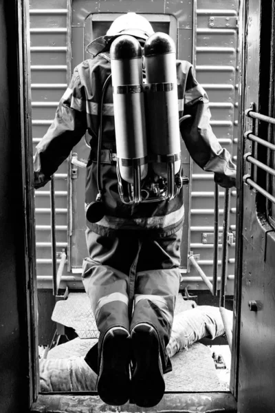 Bombero con uniforme protector de pie junto a un tren de bomberos . — Foto de Stock