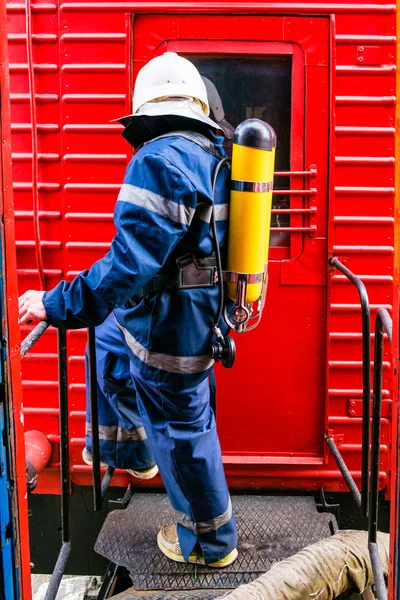 Fireman wearing protective uniform standing next to a fire train. — Stock Photo, Image