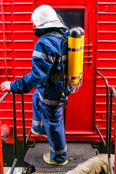 Hasák na ochranné uniformě stojící vedle požárního vlaku. — Stock fotografie