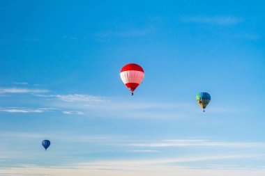 Mavi gökyüzünde renkli sıcak hava balonları.