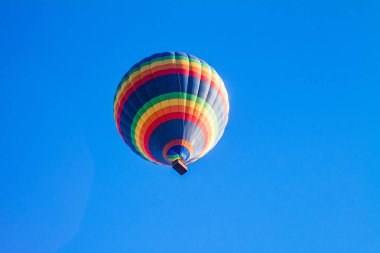Mavi gökyüzünde renkli sıcak hava balonları.