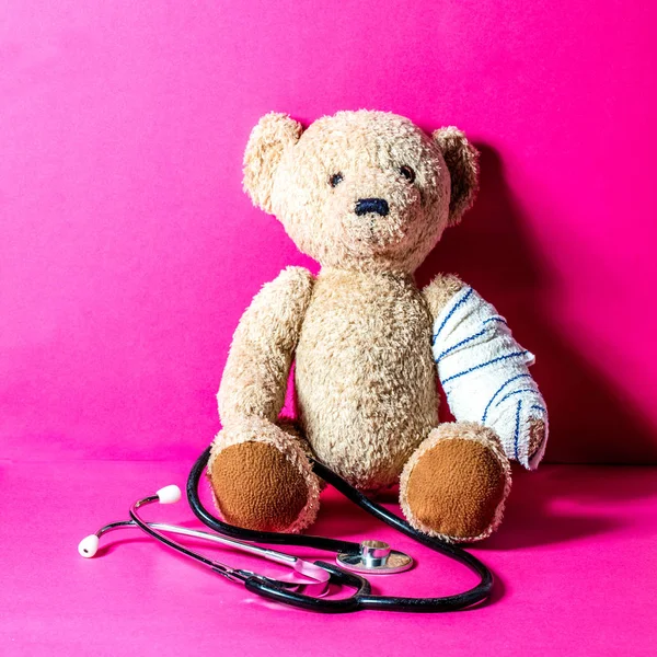 Conceito de criança brincando médico com ursinho de pelúcia, fundo rosa — Fotografia de Stock