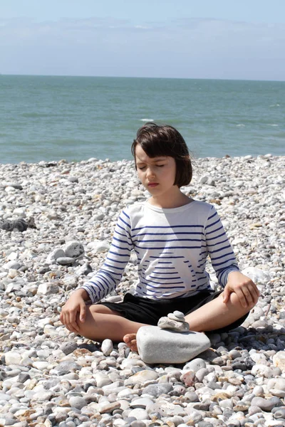 Eyes closed child relaxing for yoga and mindfulness on pebbles — Stock Photo, Image