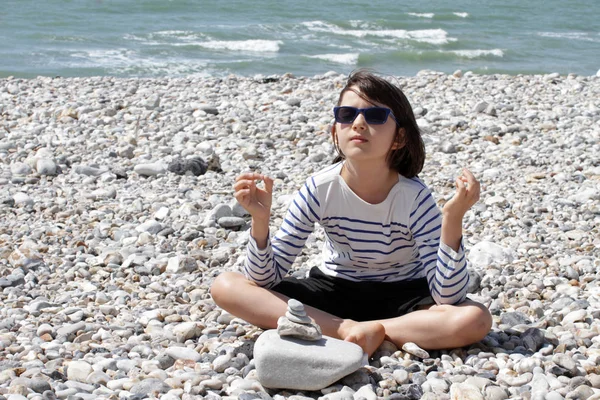 relaxed child with sunglasses on a zen pebble ocean beach