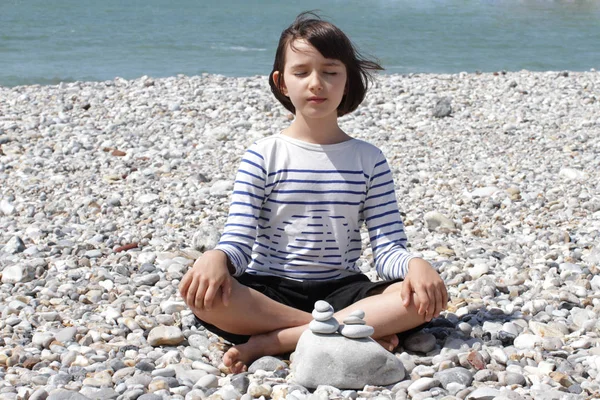 Happy child meditating on a mineral beach for relaxation and energy — Stock Photo, Image