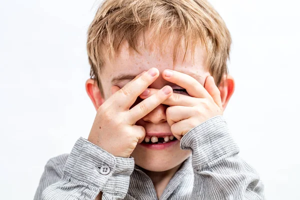 Tersenyum anak dengan gigi hilang menyembunyikan wajah untuk bermain peekaboo — Stok Foto