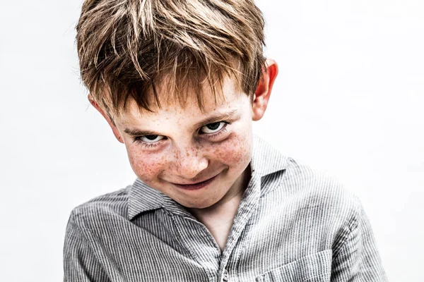 Игривый мальчик улыбается, смущенно ищет застенчивый детский юмор — стоковое фото