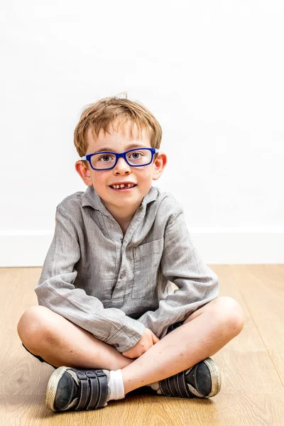 Tranquilo niño estudioso con gafas y un diente faltante sentado — Foto de Stock