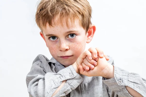 Усміхнена дитина з блакитними очима виглядає рішуче, тримаючи кулаки — стокове фото