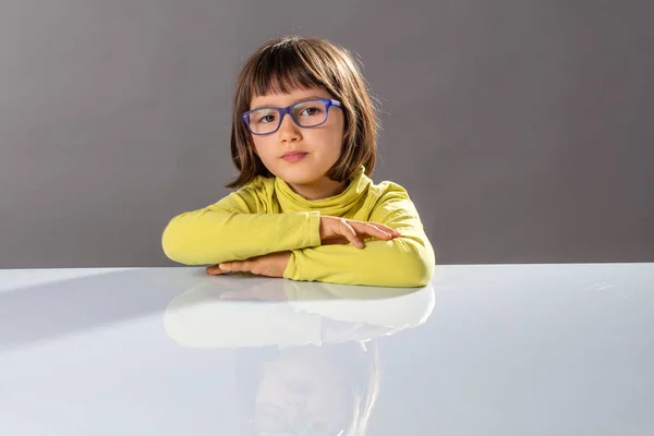 Menina adorável com óculos pensando, sonhando acordado para ideias, fundo cinza — Fotografia de Stock