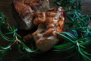 Izgara et parçaları dışında koyu kabuk ve ahşap kesim tahtasında taze biberiye..