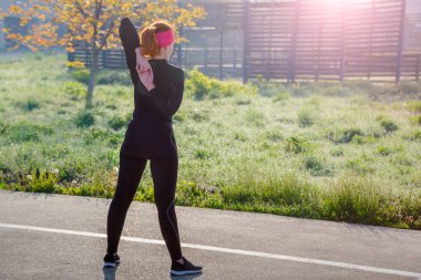Genç Avrupalı bir kadının güneşli bir günde spor parkında spor yaparken çekilmiş fotoğrafı. Açık havada eğitim kavramı.