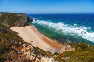 Atlantik Okyanusu 'nun kayalık kıyısı. Yüksek uçurumlar, köpüklü dalgalar ve kumsal manzarası. Güneşli yaz deniz manzarası. Portekiz Rivierası. Cabo da Roca bölgesinde. Portekiz.