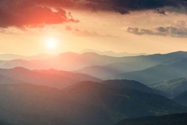 Puslu bahar dağları manzarası. Gün batımında sisli yeşil dağlar ve tepeler. Doğa geçmişini kavra.  