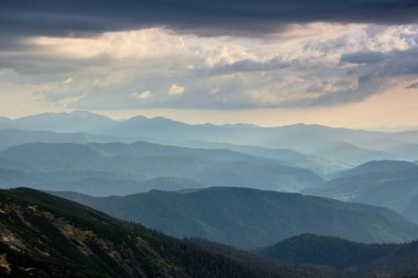 Puslu bahar dağları manzarası. Gün batımında sisli yeşil dağlar ve tepeler. Doğa geçmişini kavra.  