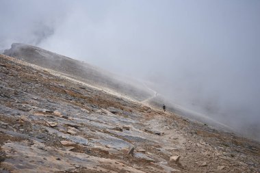 Kayalık bir patika boyunca yürüyen turistler. Yüksek dağ yamaçlarının manzarası. Dağ yürüyüşü. Olimpos Dağı 'nda gezinti. Yunanistan. Ulusal Park.