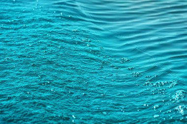 Deniz yüzeyinde hafif dalgalar ve kabarcıklar var. Tedirgin okyanus yüzeyinin doğal dokusu. Seçici odak.