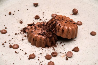 Çikolata kırıntılarıyla çevrili lezzetli çikolatalı tatlılar. Bu cazip görüntü, çikolatanın zengin dokularını ve hoşgörülü cazibesini yakalar..