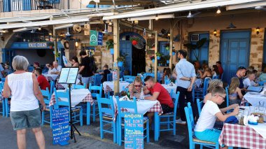 Chania, Girit - 22 Haziran 2019: Girit 'teki bir Yunan restoranında insanlar. Sandalyeler ve masalar mavi.