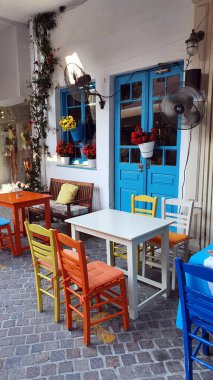 İnsansız Yunan restoranı. Dışarıda renkli sandalyeler ve masalar.
