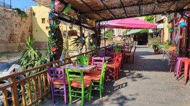 Chania, Girit - 22 Haziran 2019: İnsansız Yunan restoranı. Dışarıda renkli sandalyeler ve masalar.