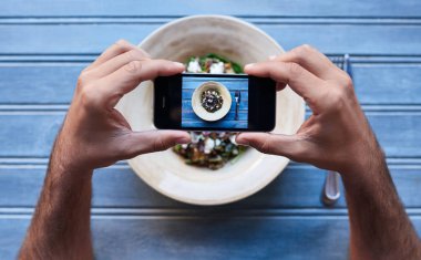 Bir bistro masada otururken onun smartphone ekran çerçeveye onun lezzetli karışık organik salata resmini kullanan adam 