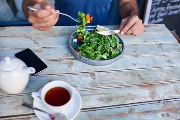 年轻人独自坐在小酒馆的餐桌上喝茶 吃着一盘美味的混合沙拉 — 图库照片