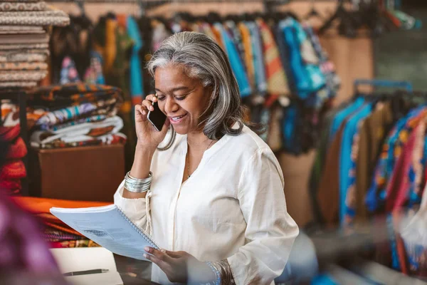 Smiling Mature Fabric Shop Owner Reading Paperwork Talking Cellphone While — Stock Photo, Image