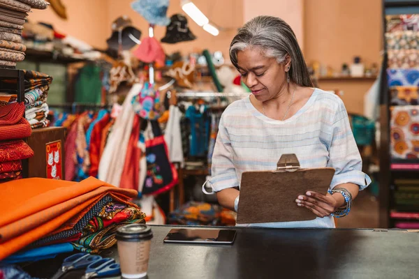 Mature Fabric Shop Owner Holding Clipboard Looking Digital Tablet While — Stock Photo, Image