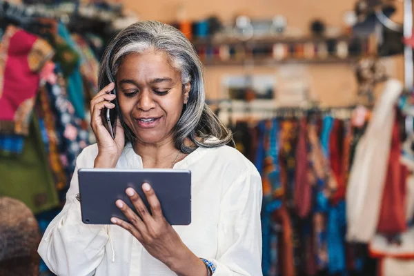 Smiling Mature Fabric Shop Owner Talking Cellphone Working Digital Tablet — Stock Photo, Image