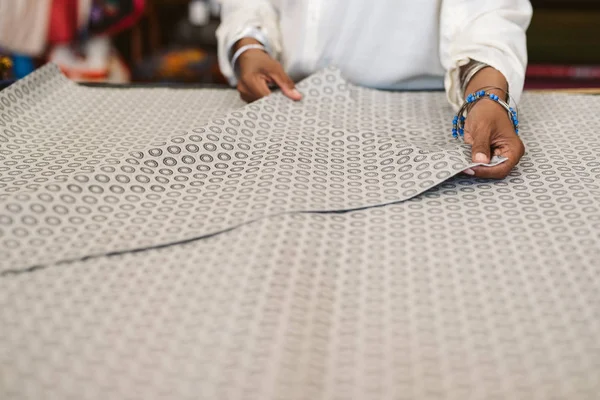 Closeup of a female fabric shop owner standing at a counter inspecting a piece of beautiful cloth