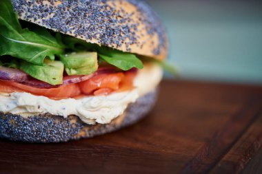 Lezzetli somon ve krem peynir haşhaş tohumu çörek rustik turkuaz ahşap bir masa üzerinde bir hizmet gemide dinlenme sebzeli closeup 