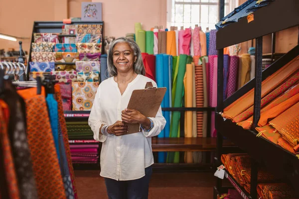 Portrait Smiling Mature Fabric Shop Owner Holding Clipboard While Standing — Stock Photo, Image