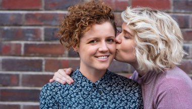 Gülümseyen kız arkadaşı birlikte bir tuğla duvarın dışında önünde ayakta iken yanağından öpmek sevgi genç kadın