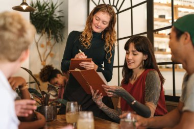 Onun menü düzeni gülümseyen bir garson kıza vererek sipariş bir bistro masa arkadaşlarınızla oturup dövmeli genç kadın