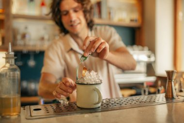 Gülümseyen genç erkek barmen renkli bir kokteyl hazırlama bar trendy tezgahın arkasında, closeup