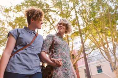 Bir gün birlikte tadını çıkarırken şehri bir sokakta gülümseyen genç lezbiyen çift el ele yürüyüş aşağı