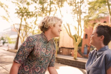 Genç lezbiyen çift birlikte şehirde güneşli bir günün tadını çıkarırken bir sokakta dans gülüyor