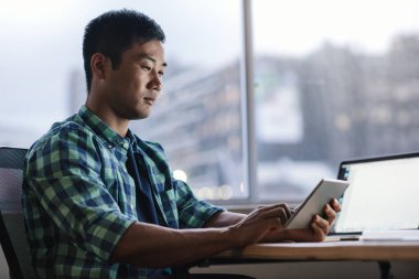 Tek başına geç saatlere kadar modern bir ofiste onun masasında otururken dijital tablet kullanma genç Asya tasarımcı odaklı