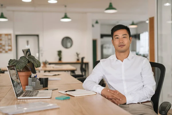 ノート パソコンでの作業と近代的なオフィスに彼の机に座ってメモを書く自信を持って若いアジア実業家の肖像画 — ストック写真