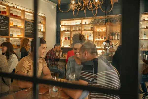 Diverso Grupo Amigos Sonrientes Hablando Sobre Bebidas Mientras Sientan Juntos —  Fotos de Stock