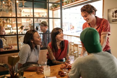 Garson garson gülümseyerek lezzetli taze tapas bir restoranda bir masada oturan bir müşteri grubu için yapılmış