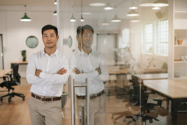 Уверенный Молодой Азиатский Бизнесмен Прислонившись Руками Стеклянной Стене Большом Современном — стоковое фото