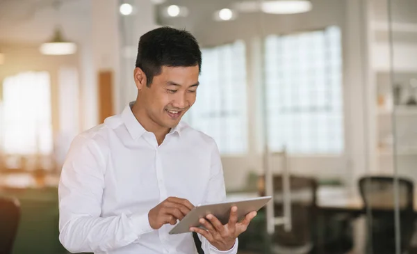 年轻的亚洲商人独自站在一个大型的现代化办公室 在一个数字平板电脑在线工作微笑 — 图库照片