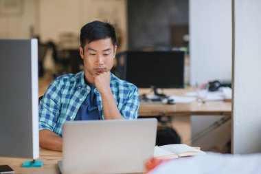 Eserleri ile bir dizüstü bilgisayar çevrimiçi çalışıyorsanız modern ofisindeki onun masasında otururken genç Asya tasarımcı odaklı