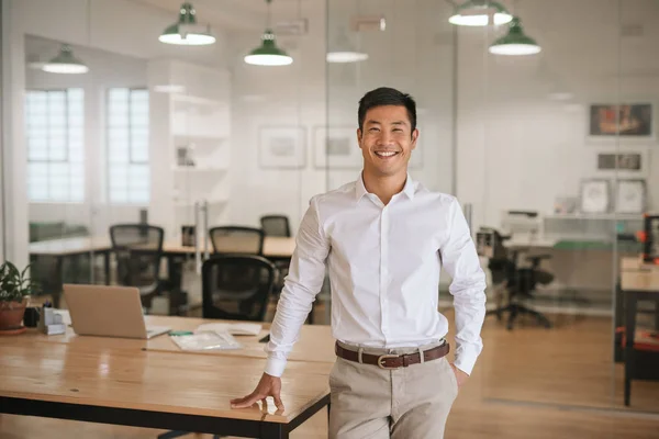 Sonriente Joven Empresario Asiático Pie Junto Una Mesa Mientras Trabaja — Foto de Stock