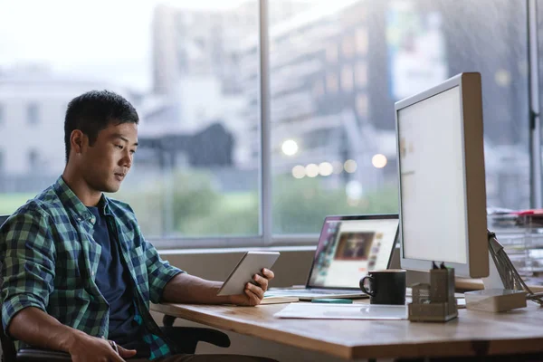 Geç modern bir ofiste çalışırken dijital tablet kullanma onun masasında oturan genç Asyalı Tasarımcısı