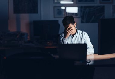 Genç Asyalı işadamı arıyor kafasıyla elinde yalnız bir ofiste geç onun masasında geceleri çalışırken yorgun
