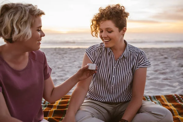微笑的年轻女同志情侣坐在一起在毯子在海滩上设置蜡烛之前看日落 — 图库照片